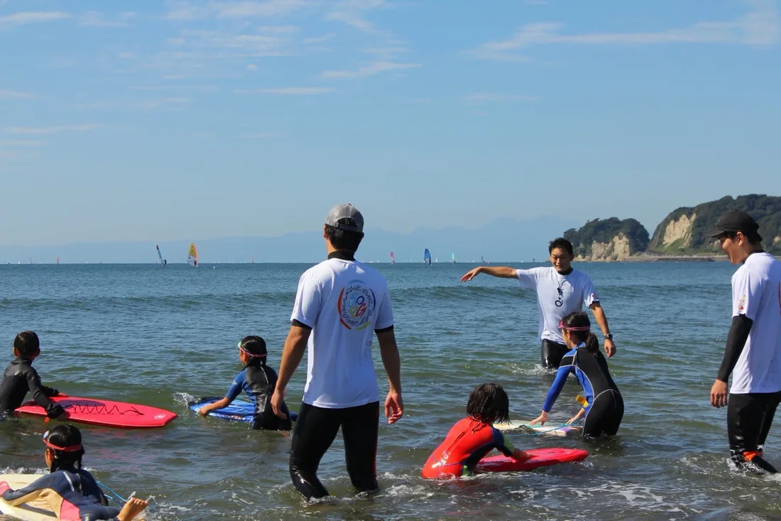 材木座の海で、スタッフと子どもたちがボディボードで遊んでいる様子